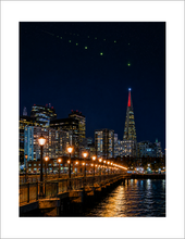 Load image into Gallery viewer, Night view from Pier 7 with lens flare, featuring the Transamerica Pyramid and San Francisco skyline.
